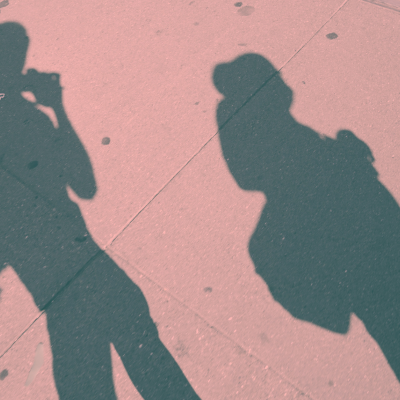 Two shadows of teenage schoolkids cast on a sidewalk