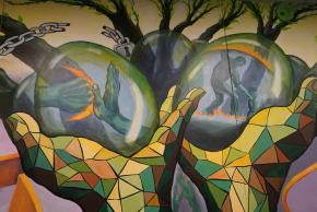 Close-up of mural scene featuring hands in front of tree cradling eggs with various scenes visible inside.