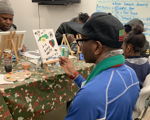 A man paints a canvas; a healing space of the arts with the RISE Project