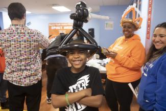 Young boy in balloon hat smiles at Spirit of Queens festival at the Queens Youth Justice Center