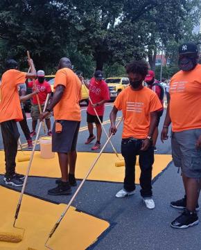 Queens Community Justice Center staff and volunteers outside painting a roadway