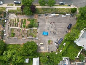 Overhead shot of community garden with people gathered in a circle before mural painting.